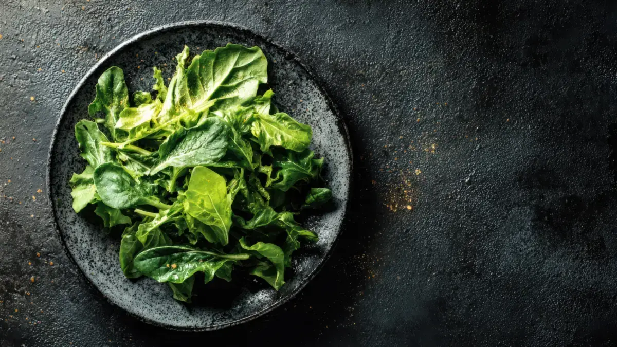 Fresh spinach and leafy green vegetables on a dark plate