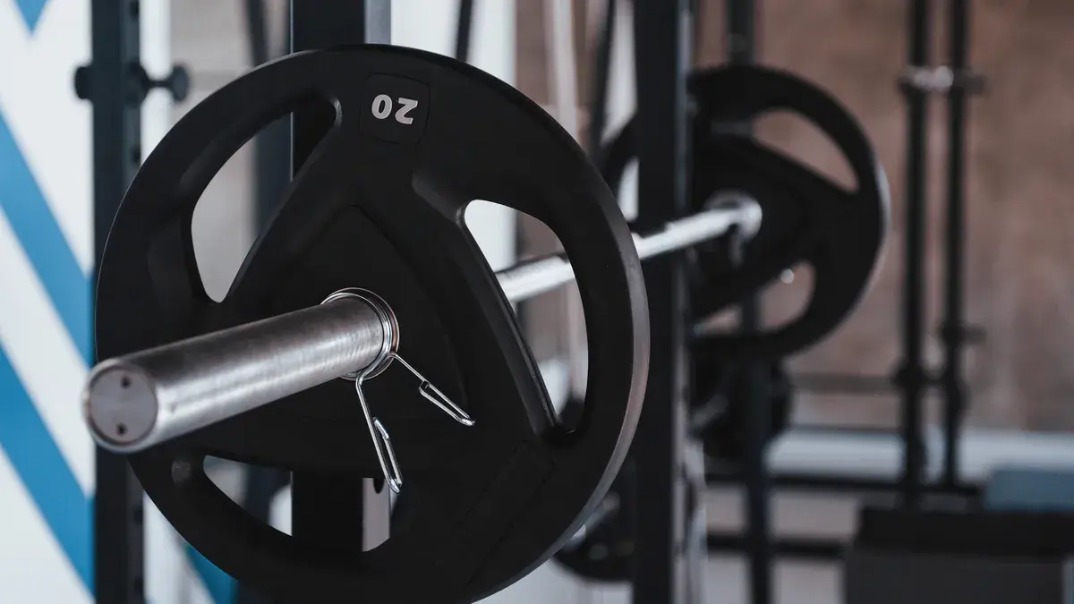A loaded barbell resting on a rack in an empty gym