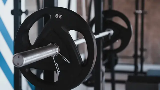 A loaded barbell resting on a rack in an empty gym