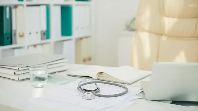 A stethoscope and medical notes on a desk in an empty consultation room