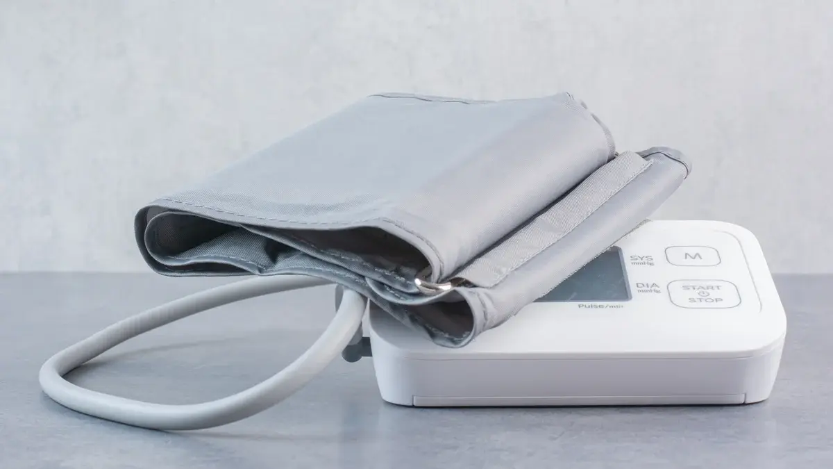A digital blood pressure monitor and cuff on a clinical work surface