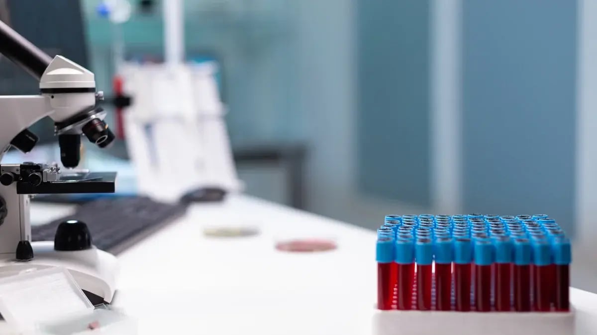 A pathology laboratory bench with a microscope and blood collection tubes